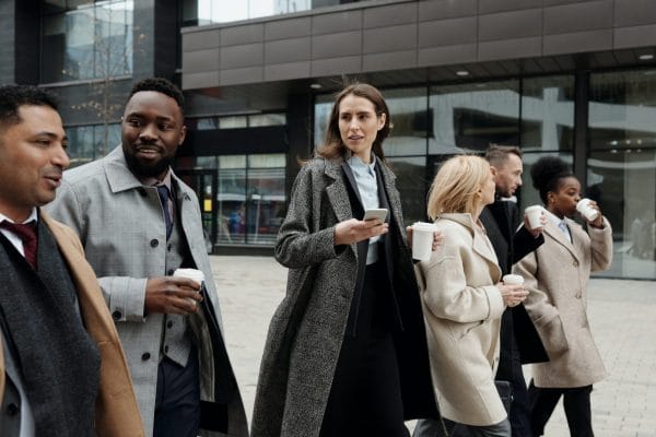A group of business leaders, diverse in ethnicity and gender, engaged in conversation outside a modern building, demonstrating the importance of networking under the Xseed Lead approach to enhance leadership effectiveness.