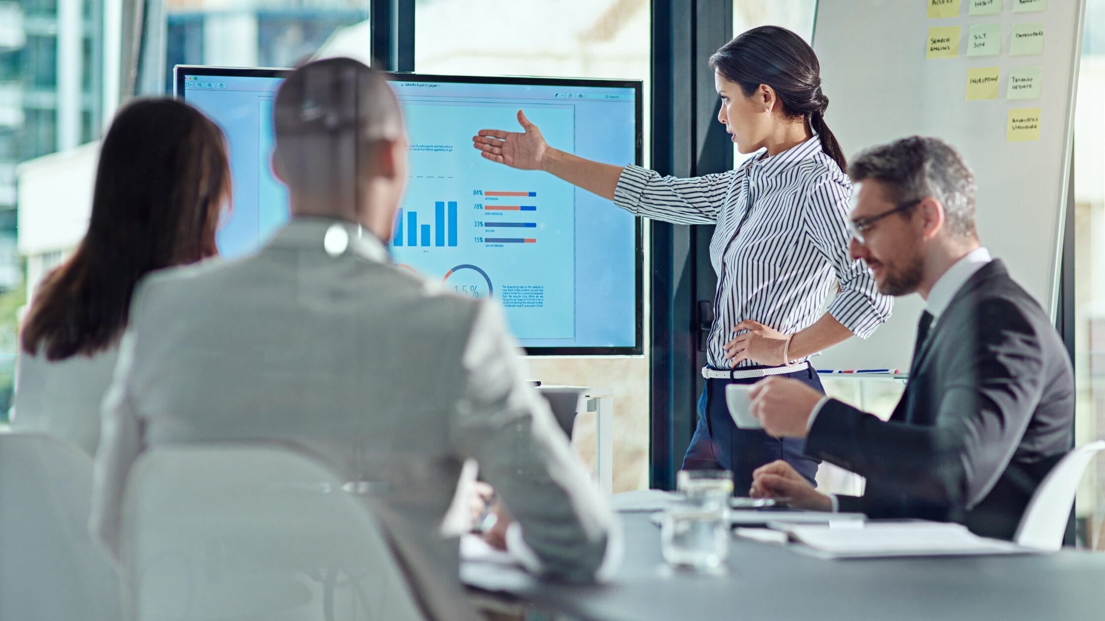 Female leader presenting stakeholder data and project metrics to a team during a strategy meeting.